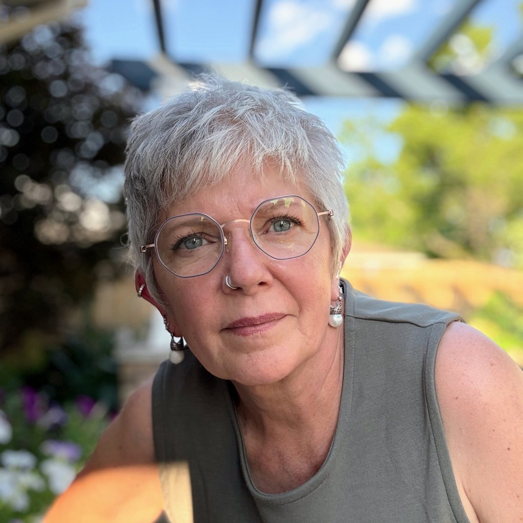 Gail is a white woman with white cropped hair, glasses and a nose ring. 