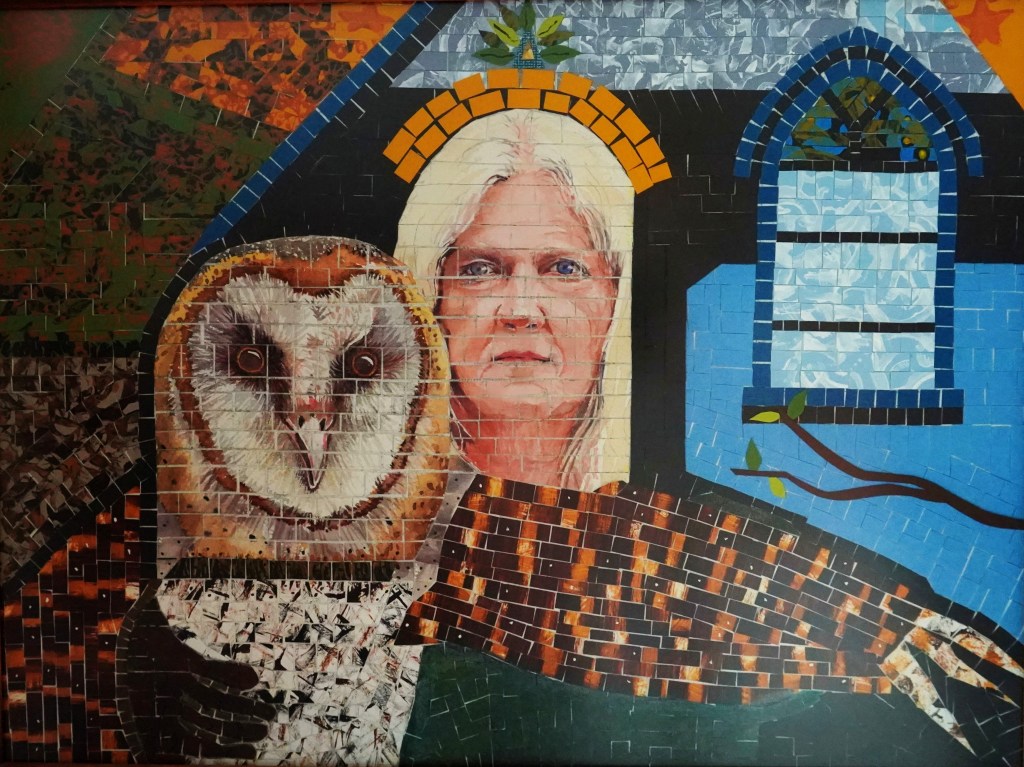 Made from tiny squares the image shows a bar owl and a woman's face very large looking out through the door of a church. 